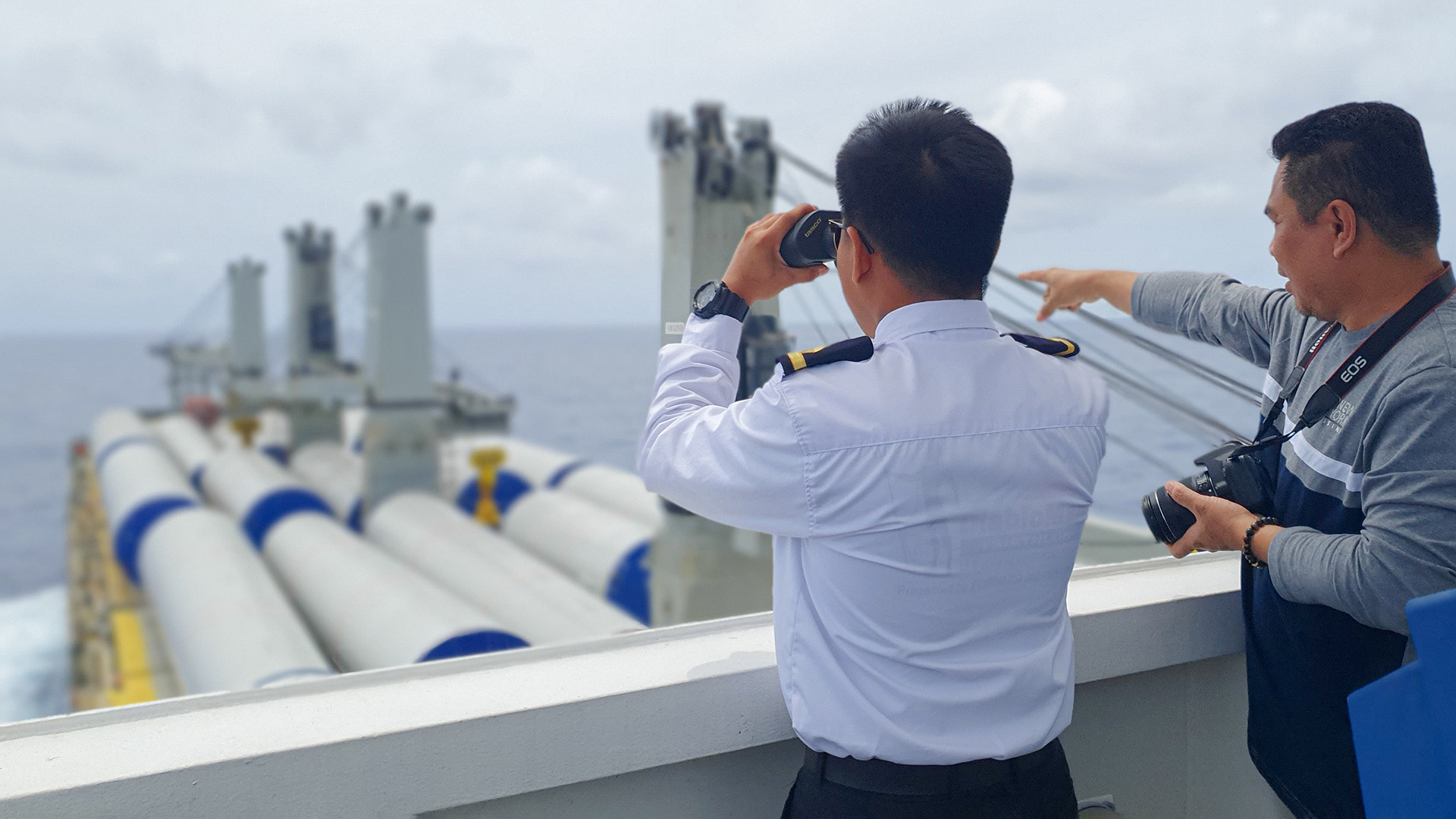 An officer onboard a ship with binoculars.